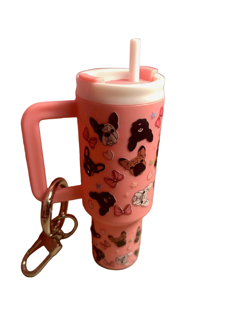 Pink tumbler with dog designs and a straw, attached to a keychain, on a beige surface.